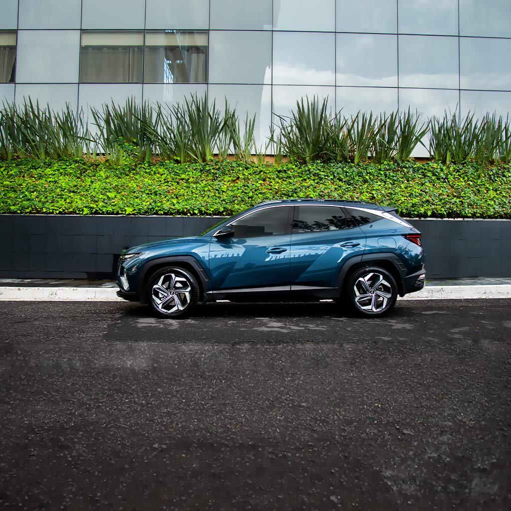 Hyundai Tucson color azul estacionada afuera de un edificio corporativo