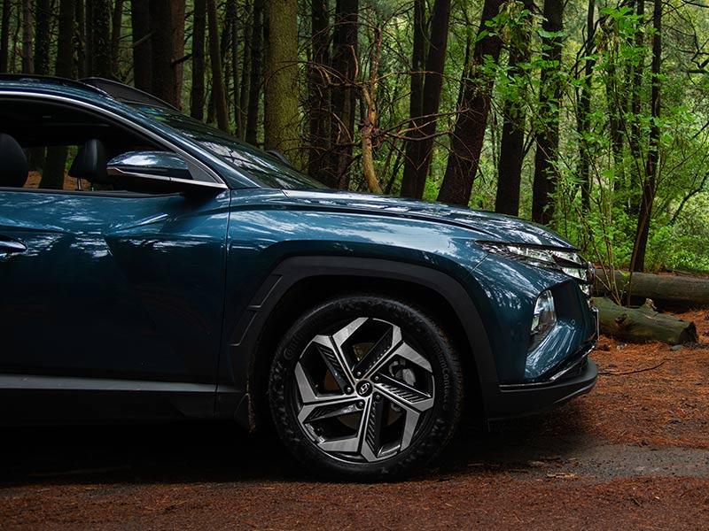 Vista lateral de Hyundai Tucson color azul en el bosque