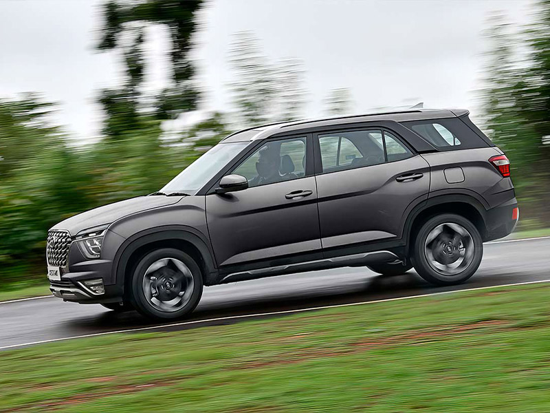 Vista lateral de Hyundai Creta Grand color plata descendiendo un camino mojado en pendiente