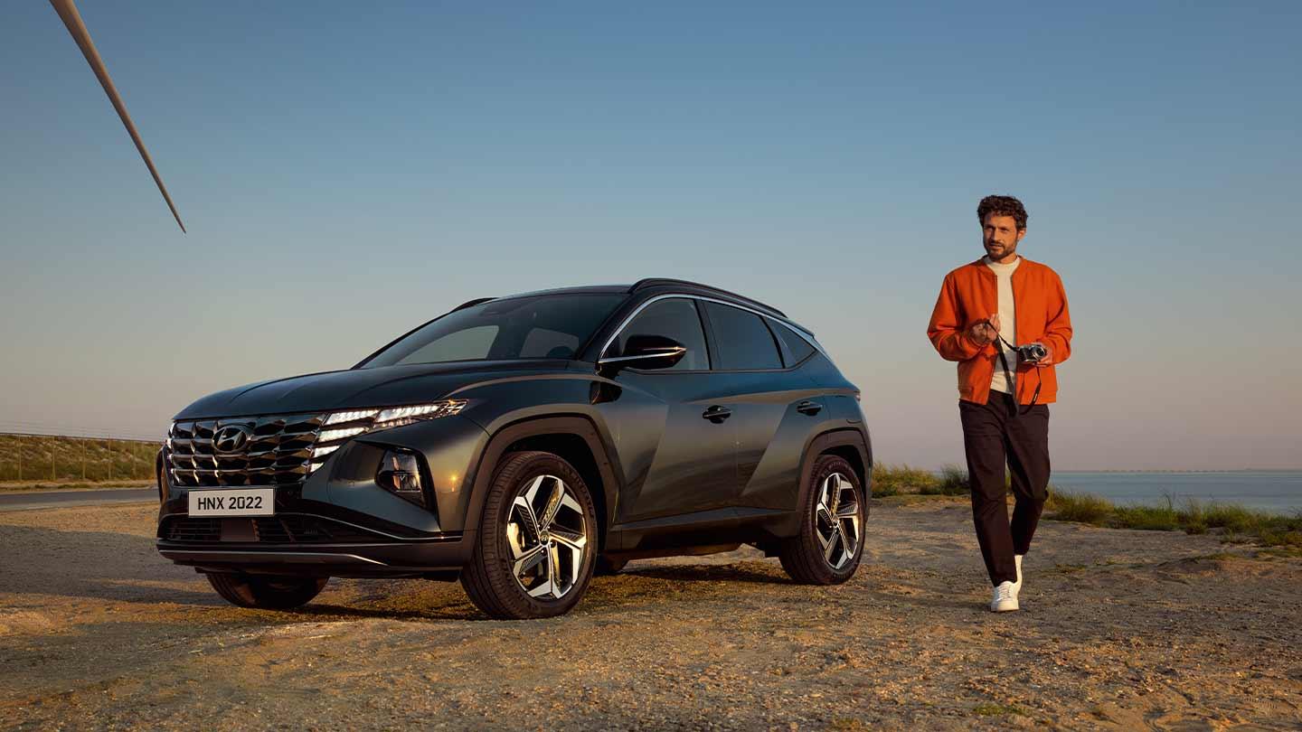 Hombre caminando junto a Hyundai Tucson en un atardecer